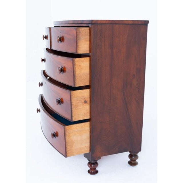 A handsome Victorian mahogany bow-front chest of drawers, standing on elegant turned feet The chest features a practical...