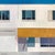 This artwork depicts a minimalist architectural scene featuring a stark white facade with large windows and a bold yellow...