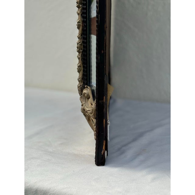 lovely sculptural antique Dutch repousse cushion wall mirror with brass and ebonized wood accents. overall height is 44”...