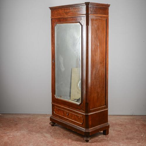This imposing single-door wardrobe represents a masterful example of 19th-century cabinetmaking, characterized by a sober...
