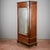 This imposing single-door wardrobe represents a masterful example of 19th-century cabinetmaking, characterized by a sober...