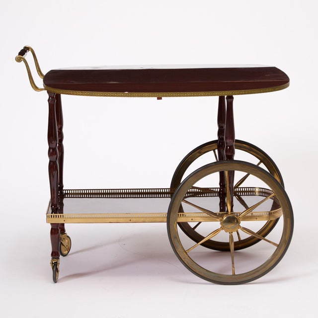 This mid-20th century bar cart is crafted in rich mahogany and accented with finely detailed brass mounts, combining...