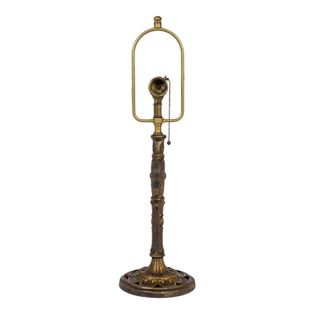 A brass table lamp with dark toned patina and gothic revival details; a radial spider web shape on the stem with a deep...