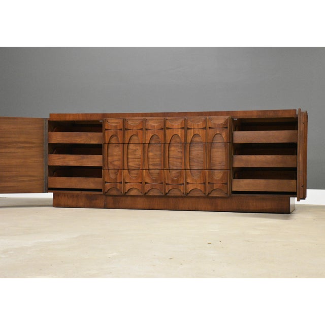 A mid century modern walnut long Tobago brutalist dresser with two doors and sculpted pulls. Made in Canada....
