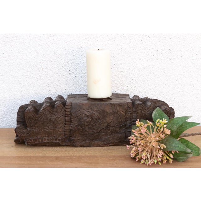This carved pedestal, is a robust fragment of Indian architectural heritage, repurposed as a commanding horizontal candle...