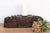 This carved pedestal, is a robust fragment of Indian architectural heritage, repurposed as a commanding horizontal candle...