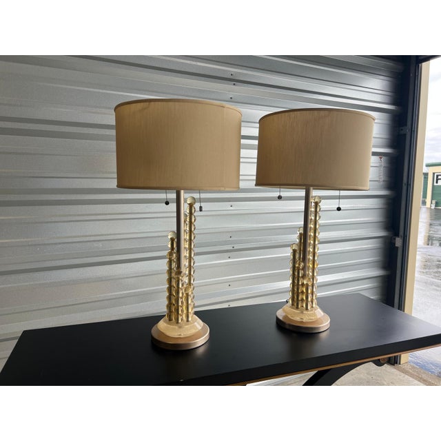 Elegant table lamps crafted circa 1960s in the Mid-Century Modern style, featuring sculptural brass columns composed of...