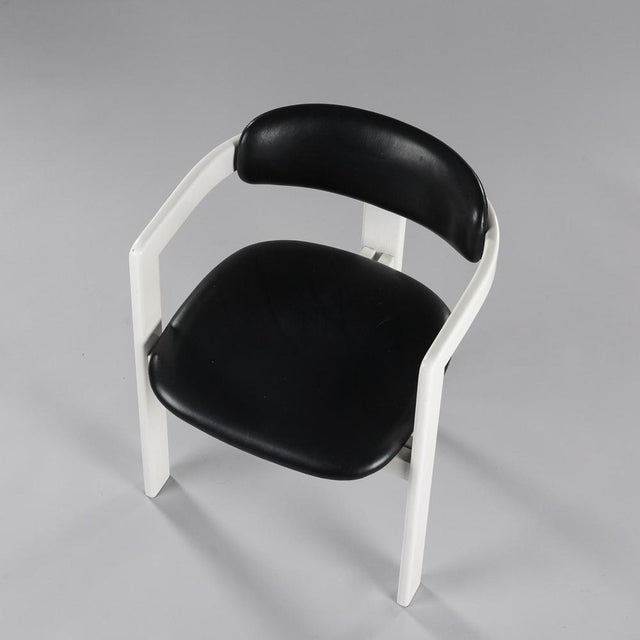 Seat armchair and black -colored faux leather back arranged on white lacquered wood structures forming the armrests and...