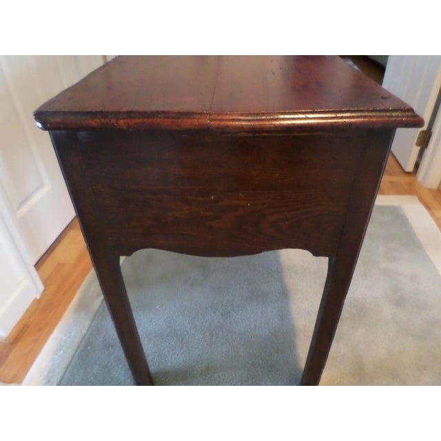 George III Oak Lowboy, circa 1780-1800, with a beautiful honey color, the overhanging top with a thumb-molded edge over a...