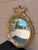 A Federal-style giltwood convex mirror crowned with a carved eagle, its wings outstretched above a laurel motif—an...