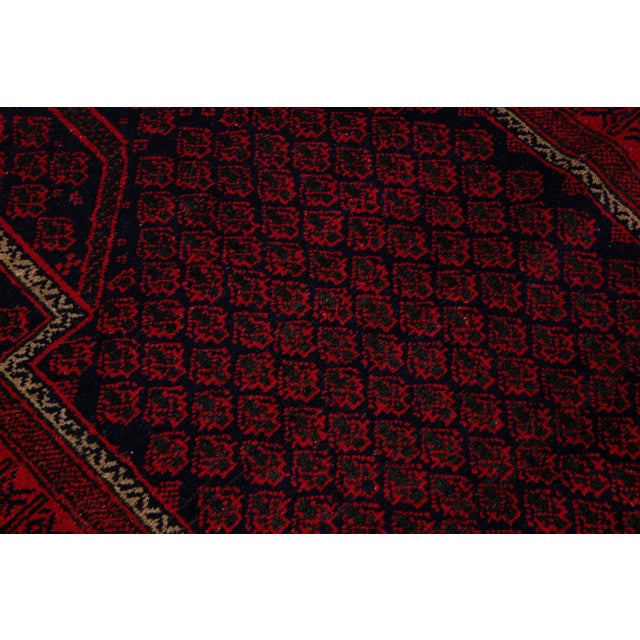 A beautiful Vintage Persian Balouch hand-knotted wool rug with a red field and multicolor accents in an all-over geometric...