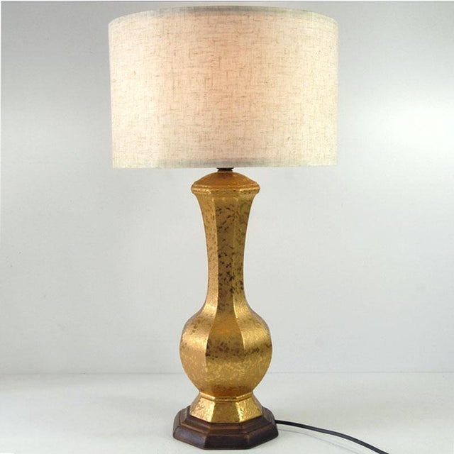 Table lamp made of ceramics, gilded and glazed. The texture of the lamp resembles hammered metal. The bottom of the base...