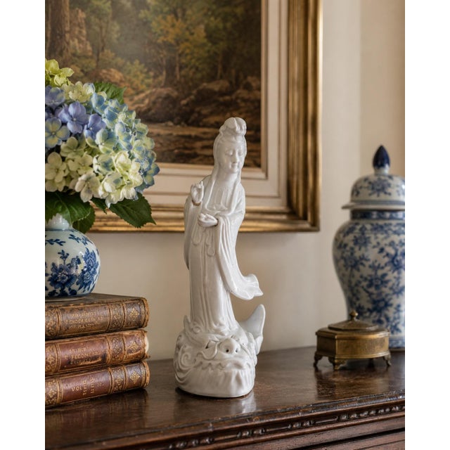 A graceful mid-20th-century Chinese blanc de chine porcelain figure depicting Quan Yin standing serenely atop a...