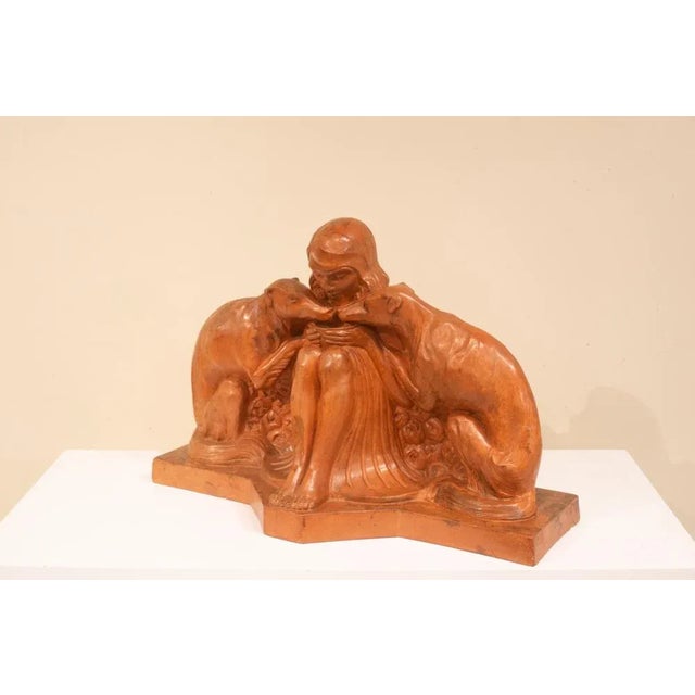 Sculpture of a seated young woman, flanked by two greyhounds drinking from a pot she holds in her hands. Piece of Armand...