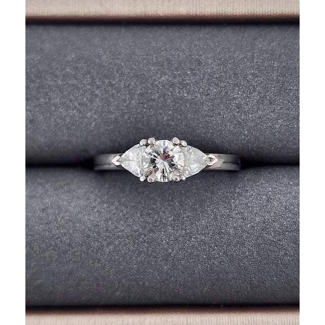 This stunning platinum ring features a brilliant round center diamond weighing 0.73 carats, radiating exceptional sparkle...