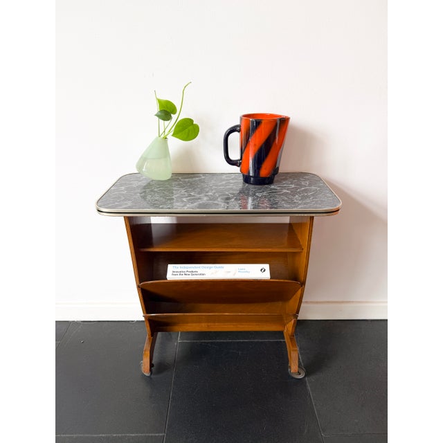 A bar cart or side table in mid-century modern style, featuring a marble-effect laminate top and wooden frame from the...