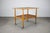 This Mid-Century Danish rolling table from the 1960s features a teak-veneered top, slatted lower storage shelf, and...