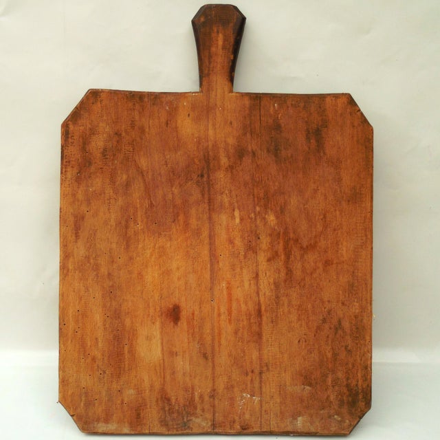 A charming, primitive-style wooden bread board featuring a hand-carved handle and unique chamfered corners. Crafted from a...