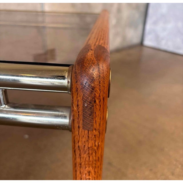 A stylish vintage side table featuring a solid oak frame, smoked glass top, and sleek chrome stretcher bars. Clean, modern...