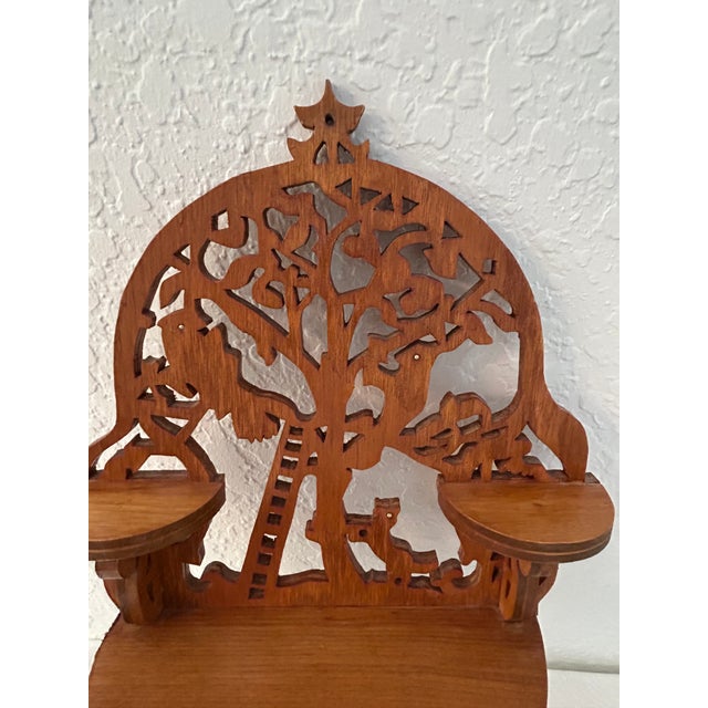Whimsical wood hanging wall shelf featuring three platforms for object display. Intricate fretwork features a ladder...