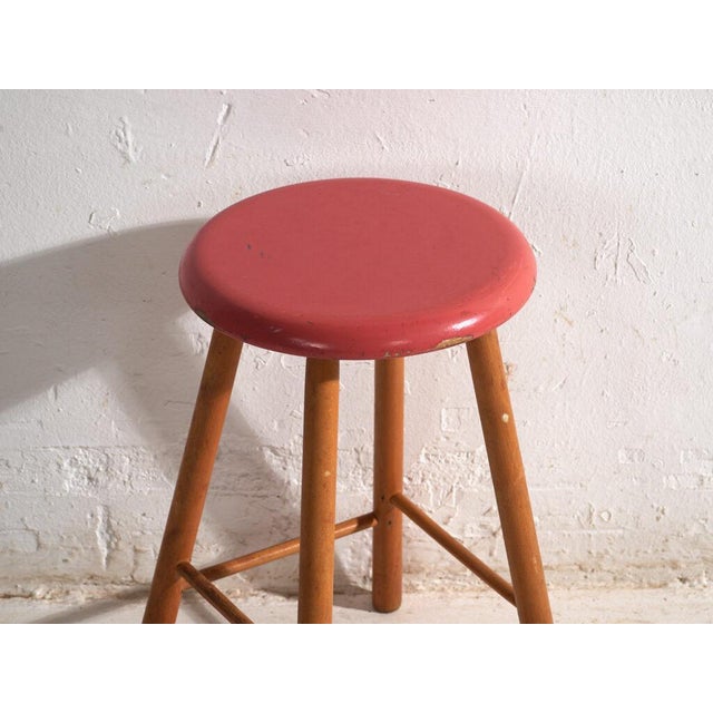 This antique wooden stool is a three-legged seat with a round seat and turned splayed legs joined by stretchers. It...