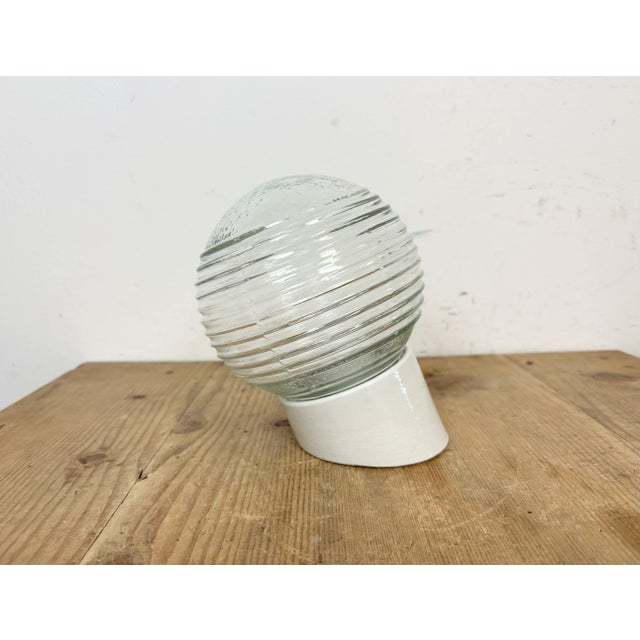 Vintage industrial light made in Poland during the 1970s.It features a white porcelain wall mounting and a striped glass...