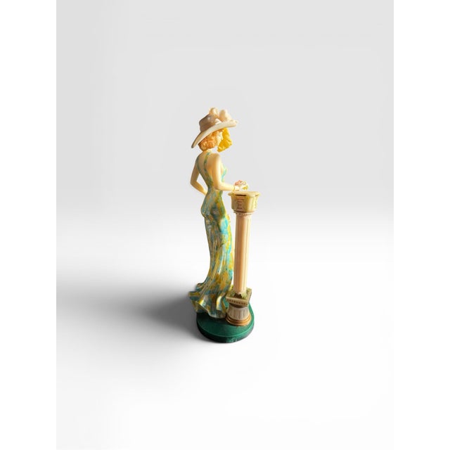 The figurine in the image is a vintage resin statue of an elegant lady leaning on a classical column, designed by the...