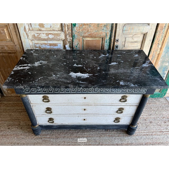 Stylish French Empire antique commode, featuring a Greek key motif design, original hardware, and lovely black marble top....