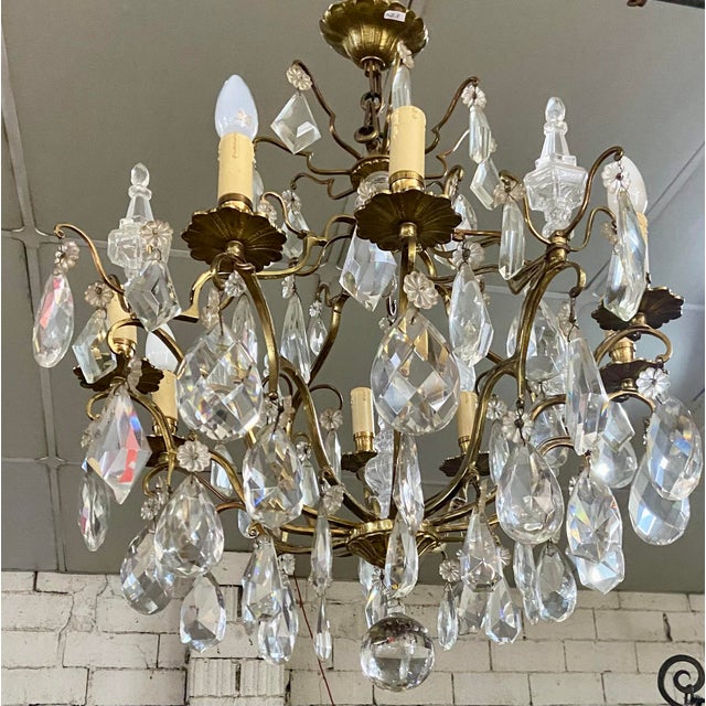 Elegant and richly ornamented French vintage chandelier in gilt bronze and cut crystal, dating from the mid-20th century....