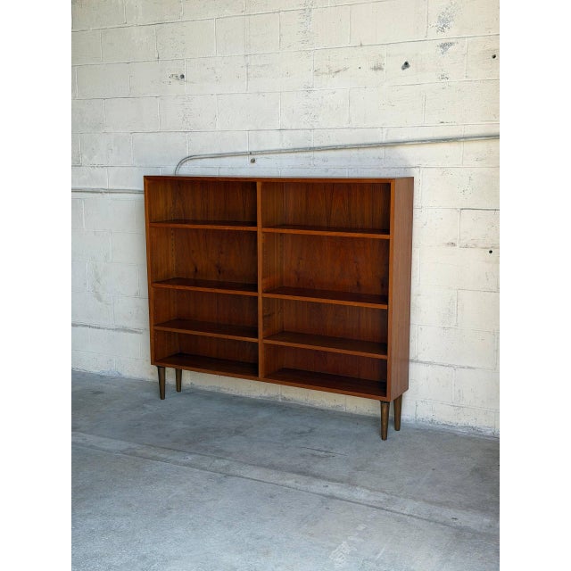 This elegant Scandinavian shelving unit features clean minimalist lines, adjustable shelves, and warm richly grained teak...