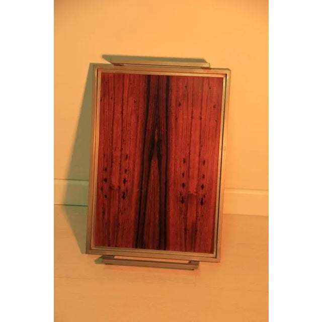 This wood and metal tray was designed in the mid-century design during the 1960s. It is made from wood, and features a...