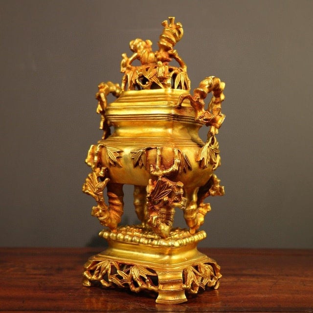 This is an ornate and substantial decorative censer (incense burner), crafted from cast bronze with a bright, golden...