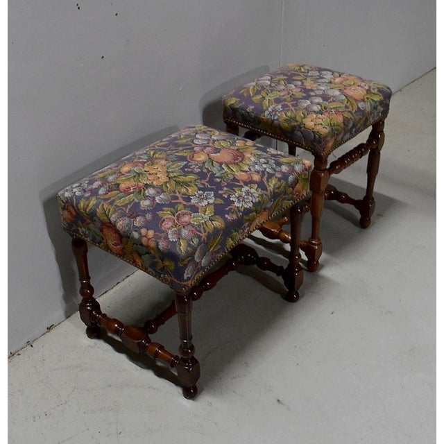 Set of two stools, in the taste of Louis of XIV, with solid walnut structure. Their tops are covered with a colored...