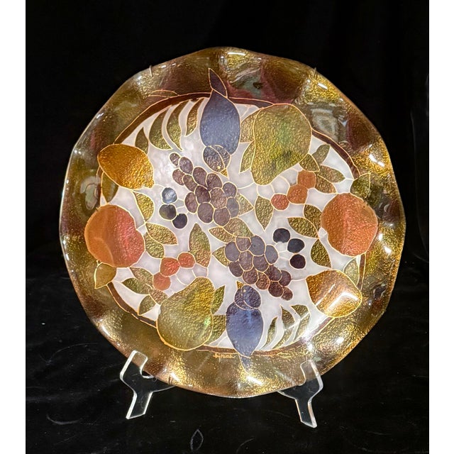 This is a decorative fused art glass plate featuring a stylized still-life motif of birds, fruits and foliage in earth...