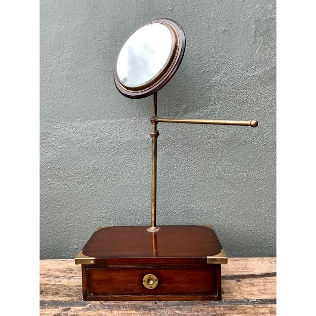 This vintage vanity mirror exemplifies the practical elegance of campaign-style furniture, combining a rich mahogany-toned...