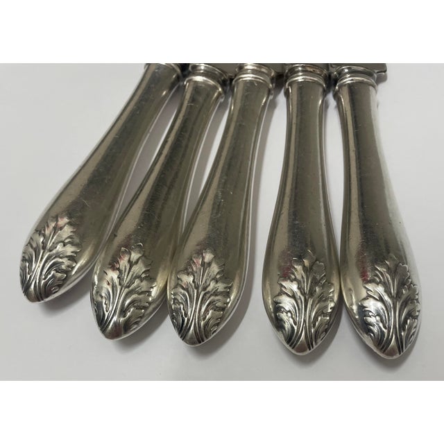 Set of five sterling handled knives with raised acanthus leaf decoration. Each handle marked, some partially rubbed. The...
