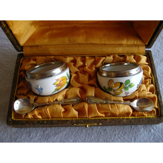In the original box they lovely set present a hand floral decor on each container with a silver rim and two silver spoons...