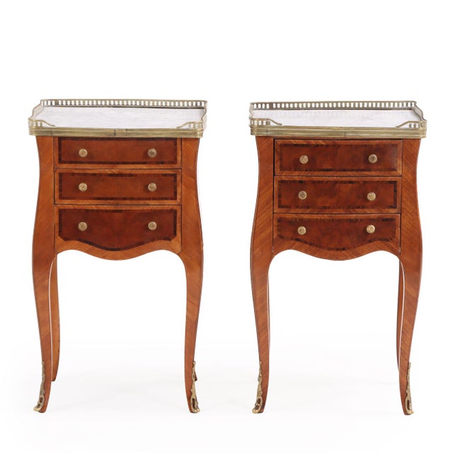 Of elegant bombe form, these tables feature shaped, galleried marble tops above a finely crafted burlwood cases with...