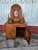 Hand-carved wooden vanity is constructed from solid wood with a natural brown finish. This piece has an ornate top section...