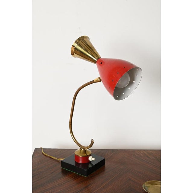 Elegant and sculptural adjustable table lamp in brass, red enameled metal and bakelite. This delightful piece was designed...