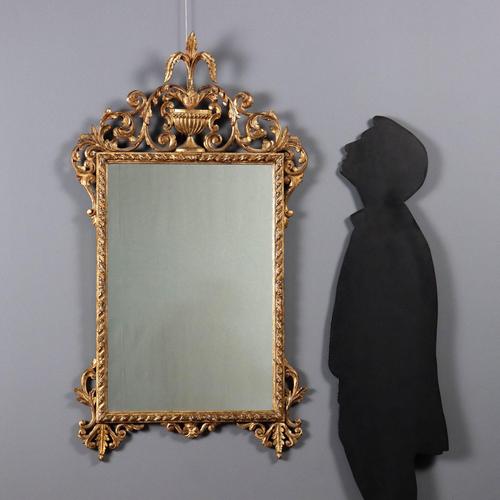 Carved and gilded wooden mirror. Frame with twisted carvings, pierced and carved frieze, with a central vase, curls and...