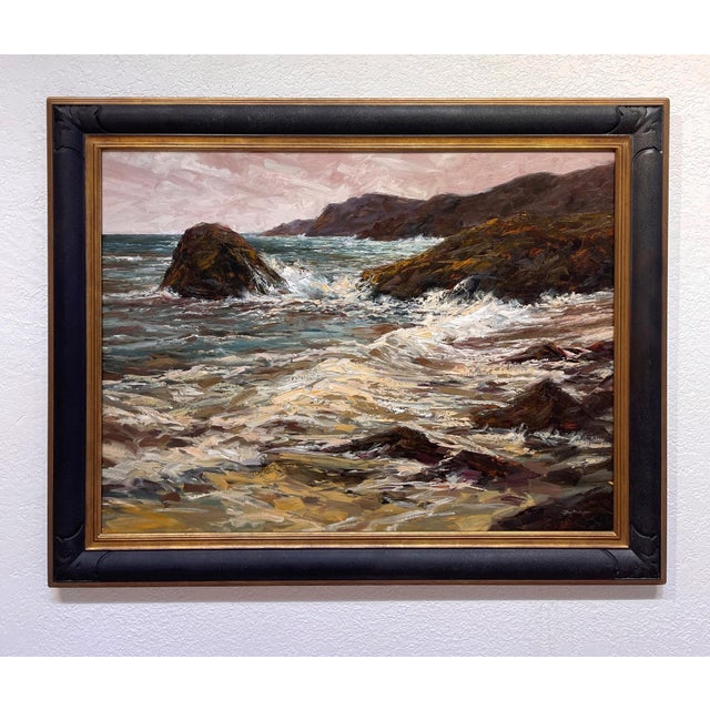 The painting captures a dynamic coastal scene, where tumultuous waves crash against rugged rocks under a moody sky. The...