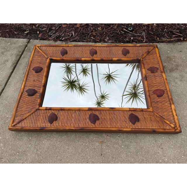 A handsome vintage wall mirror by Bassett Mirror Company featuring a woven rattan surround framed in burnt bamboo and...