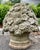 A cast stone floral basket garden ornament, featuring an abundant arrangement of molded roses, blossoms, leaves, and...