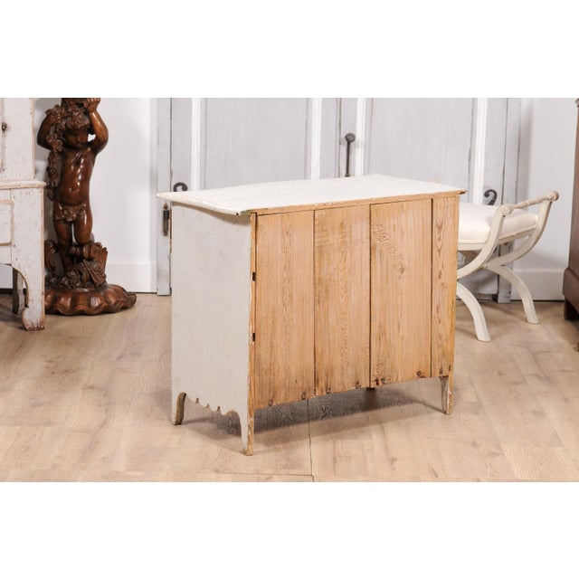 A Swedish Rococo period three-drawer commode from circa 1770 with light gray cream painted finish, carved skirt and...