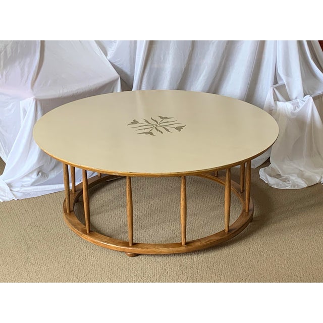This is a round coffee table in the style of John Van Koret. The table has distinctive wooden spindle legs set between two...
