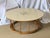 This is a round coffee table in the style of John Van Koret. The table has distinctive wooden spindle legs set between two...