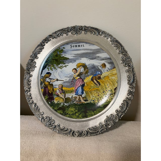 Pewter and porcelain plates depicting the four seasons of spring, summer, fall, and winter. They have a hook on the back...