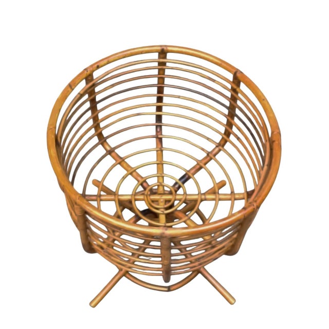 An elegant storage basket made of hand-woven natural rattan, featuring a refined goblet shape with a pedestal base....
