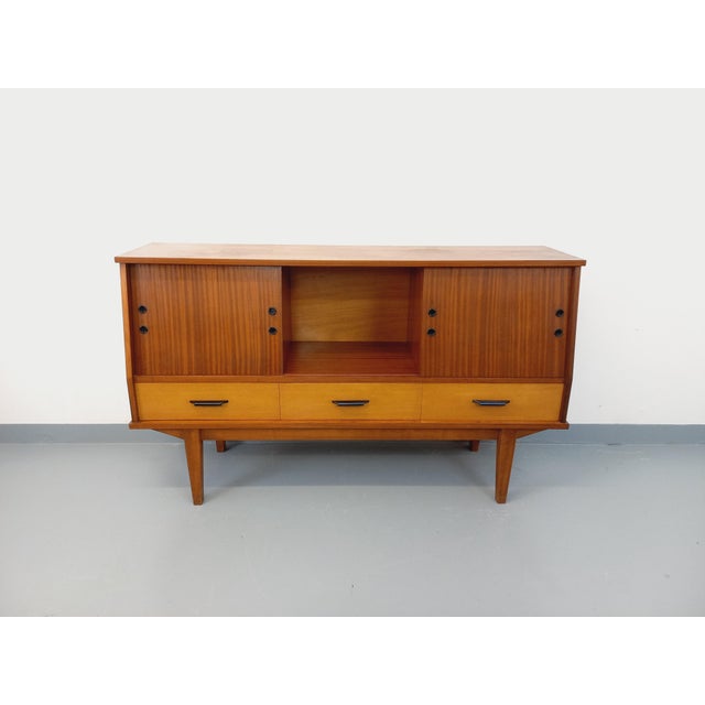 Vintage low sideboard from the 1960s, crafted from teak-style mahogany, ash, and beech wood, with black handles. Original...